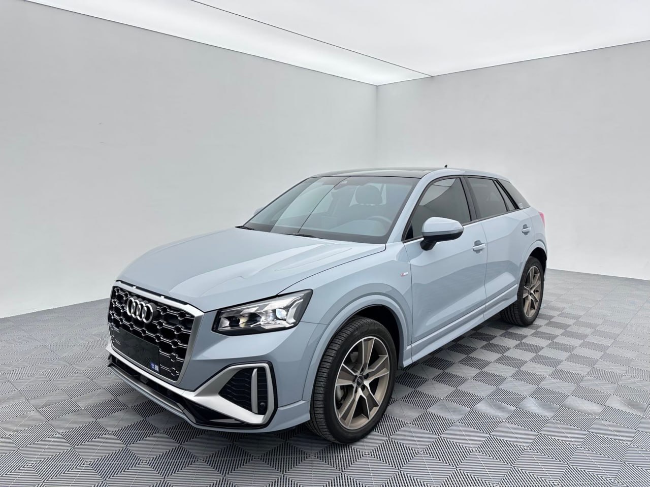 Светлый автомобиль Audi в помещении, вид спереди и сбоку.