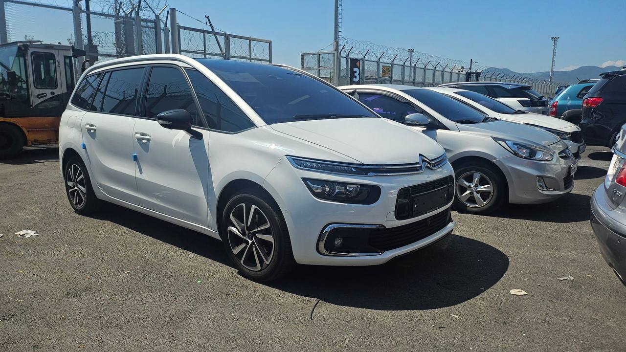 Белый Citroën на стоянке среди других автомобилей.